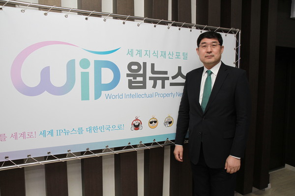Park Seong-joon Chief of Intellectual Property Trial and Appeal Board is posing in front of the photo wall of WIPNEWS.